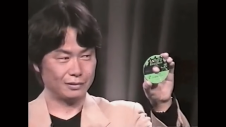 Shigeru Miyamoto holding the E3 2001 Luigi's Mansion Disc. The disc's appearance is similar to the released version, except that Luigi is in a different pose.