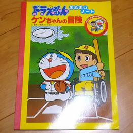 The cover to the notebook, featuring an illustration of Ken playing baseball with the help of Doraemon.