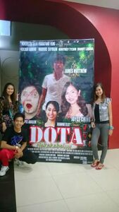 Photo of the film's cast posing in front of an alternate poster for the film