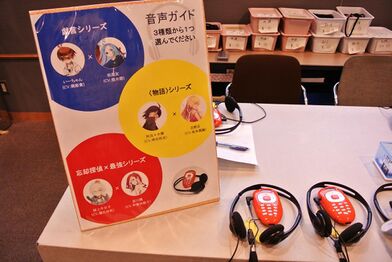 Picture of a desk where the audio guides were distributed, and a poster showing the characters in them.