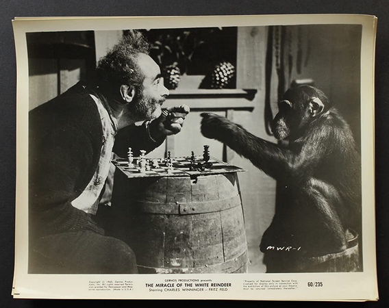 A black-and-white still frame or lobby card, showing a chess match with the chimp.