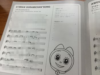 Inside of the jacket, with lyrics, definitions and sheet music in English and Japanese for "A "Draw Dorami-chan" Song". Please note that text and sheet music has been blurred out by the original uploader.