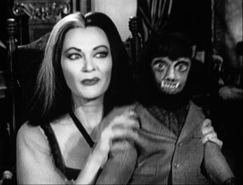 One of six screenshots of the second pilot version of My Fair Munster, taken from America's First Family of Fright, featuring Lily holding a repaired Wolf-Wolf.