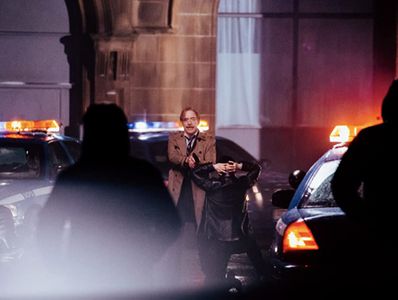 Set photo of Commissioner Gordon holding a criminal at gunpoint.