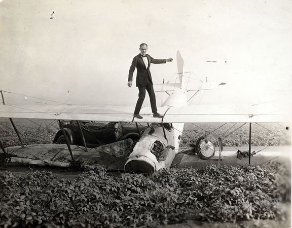 A promotional photo for the film of Ormer Locklear atop a crashed Curtis "Jenny" biplane.