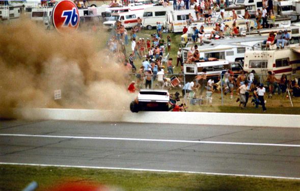 The car slides along the wall, knocking over other spectators.